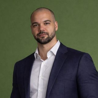 Dr. Juan Antonio Rosa, nutricionista, de terno azul-marinho sobre fundo verde